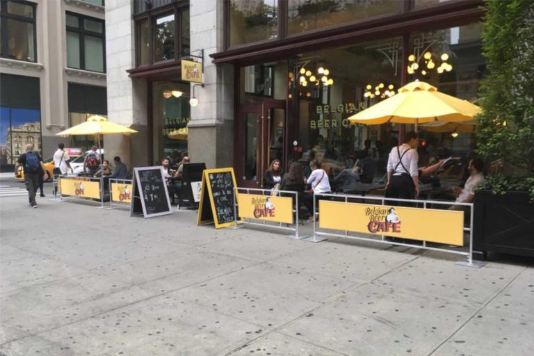 Belgian Beer Cafe outdoor seating area with sidewalk barriers and cafe partitions and umbrellas by NYC Signs & Awnings